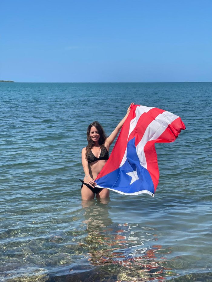Mayleen holding the Puerto Rican flag in the sea