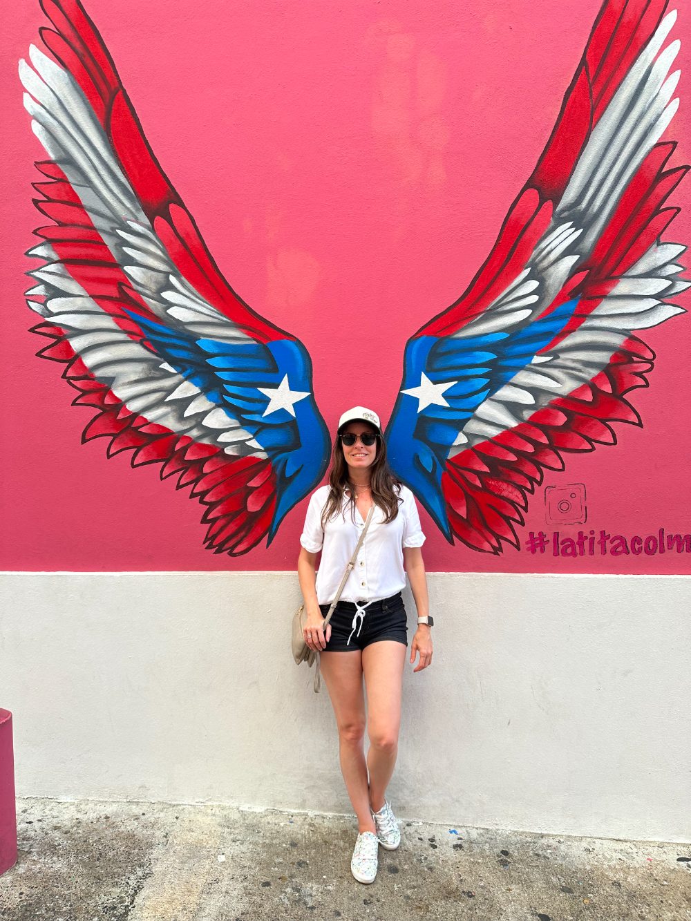 Mayleen in front of a Puerto Rican flag wings mural